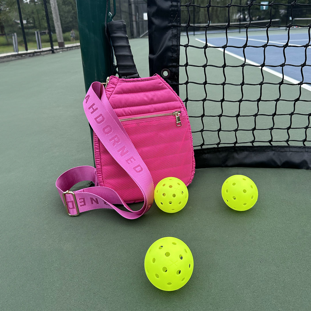 poppy pickleball racket bag with pickleballs against tennis net